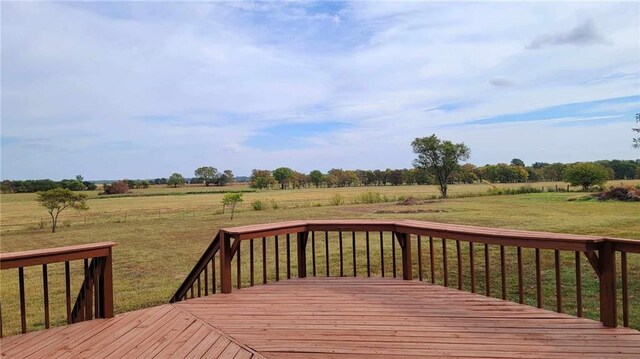 wooden terrace featuring a rural view and a lawn