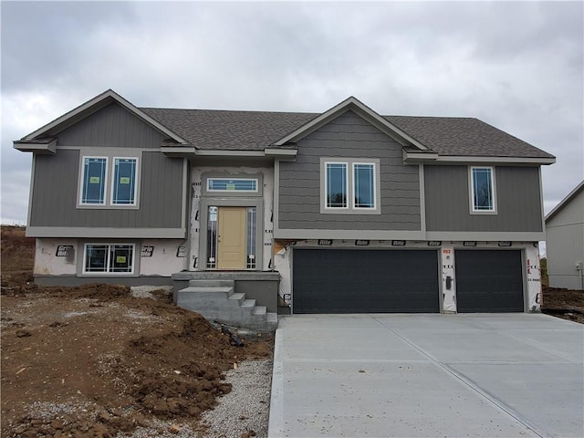 bi-level home featuring driveway, a garage, and roof with shingles