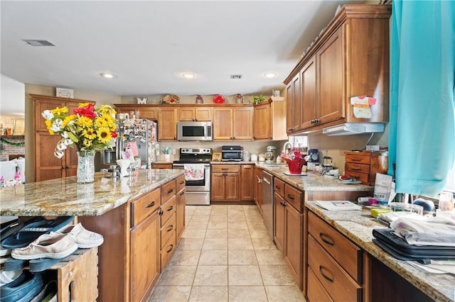 kitchen with visible vents, light tile patterned floors, brown cabinets, appliances with stainless steel finishes, and a sink