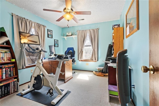 workout area with visible vents, baseboards, a textured ceiling, and ceiling fan