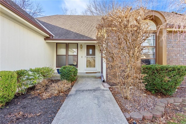 view of exterior entry with roof with shingles