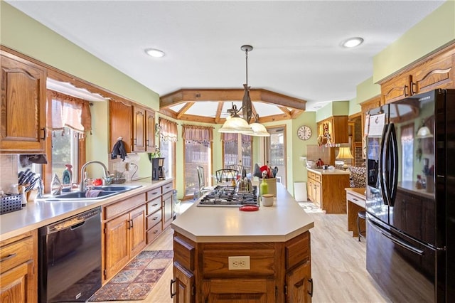 kitchen featuring black appliances, a center island, light countertops, and a sink