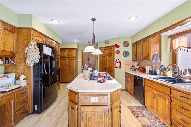 kitchen with black appliances, a sink, a kitchen island, brown cabinetry, and light wood finished floors