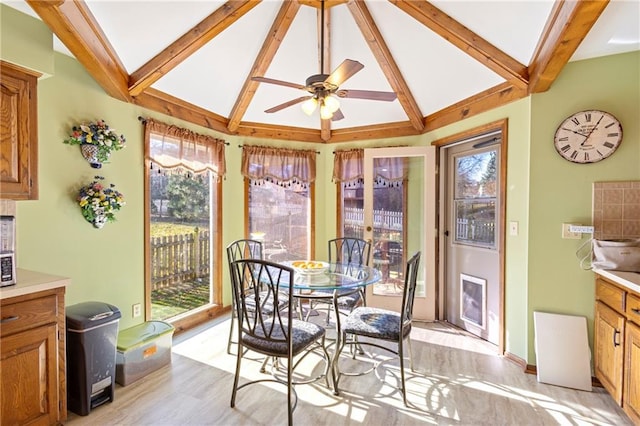 dining space with a wealth of natural light, light wood-style flooring, vaulted ceiling with beams, and a ceiling fan