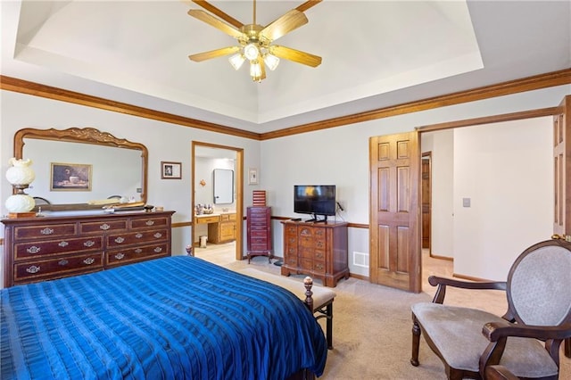 bedroom featuring a ceiling fan, a tray ceiling, light carpet, crown molding, and connected bathroom