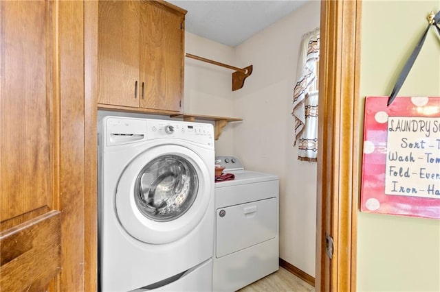 clothes washing area featuring cabinet space and washing machine and clothes dryer