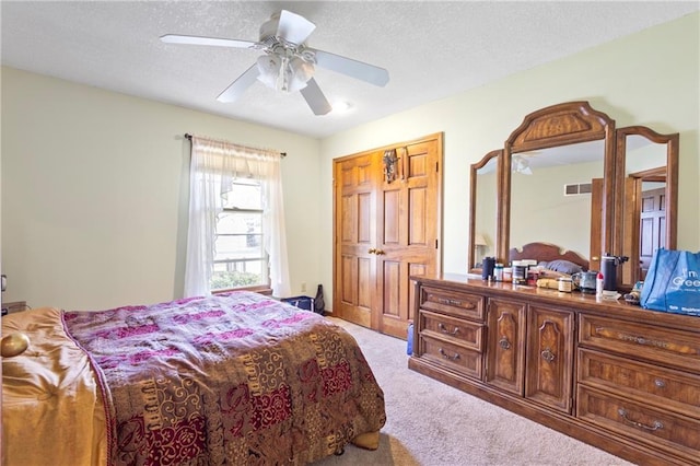 bedroom with a textured ceiling, ceiling fan, visible vents, and light carpet