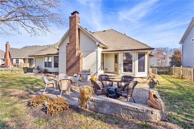 back of property featuring a lawn, a patio, a fenced backyard, roof with shingles, and a chimney