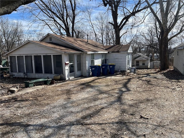 view of side of home featuring roof with shingles, driveway, and a sunroom