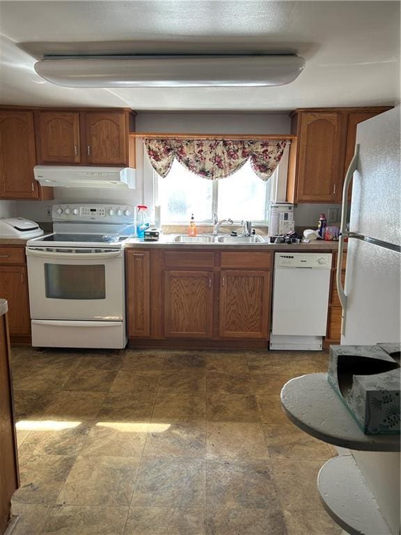 kitchen featuring brown cabinetry, white appliances, exhaust hood, and a sink