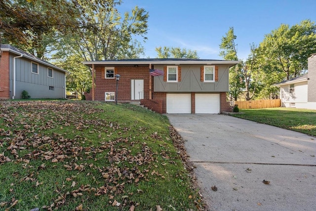 split foyer home featuring a front yard, fence, an attached garage, concrete driveway, and brick siding