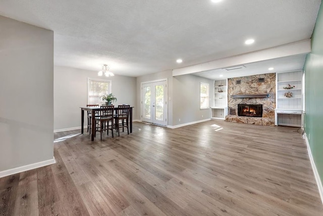 living room featuring built in features, a fireplace, baseboards, and wood finished floors