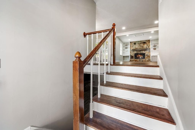 stairway with a stone fireplace, built in shelves, recessed lighting, and baseboards