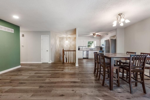 dining area with visible vents, baseboards, ceiling fan with notable chandelier, a textured ceiling, and dark wood-style flooring