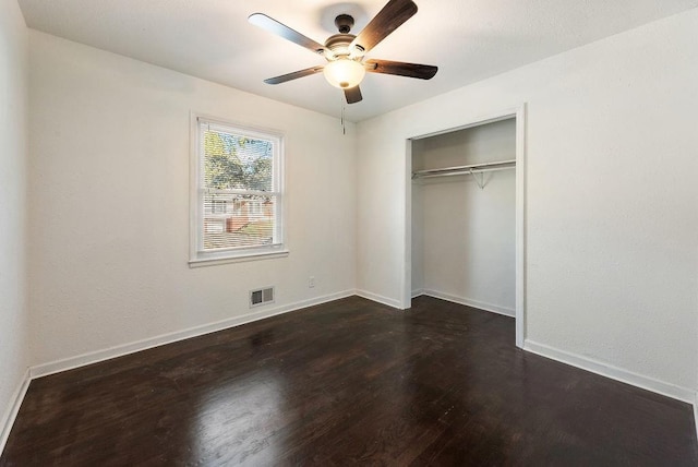 unfurnished bedroom featuring a ceiling fan, visible vents, baseboards, dark wood-style flooring, and a closet