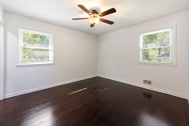 empty room featuring dark wood finished floors, baseboards, visible vents, and ceiling fan