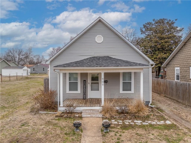 bungalow with roof with shingles, covered porch, and fence