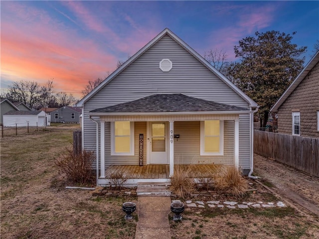 bungalow featuring a porch, fence, and roof with shingles