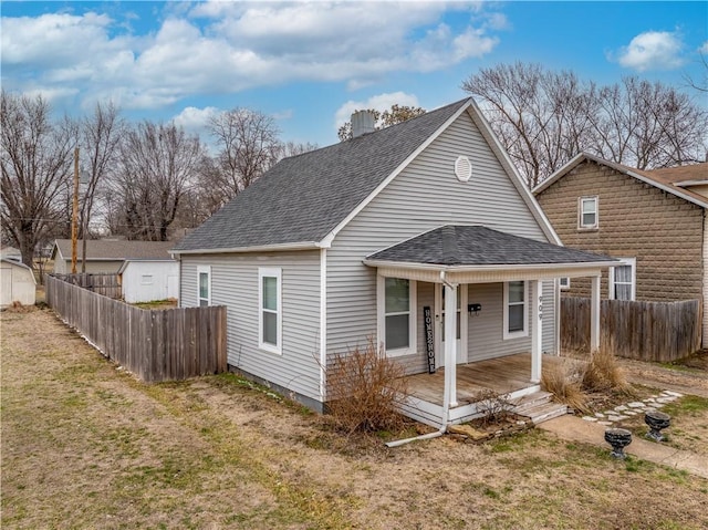 rear view of house with a lawn, a porch, a shingled roof, and fence