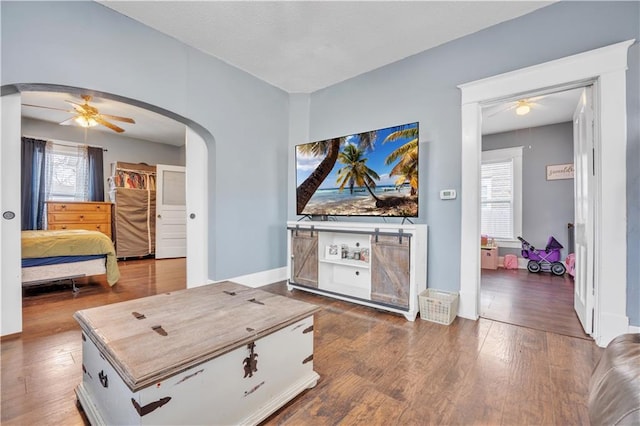 interior space with baseboards, arched walkways, and wood finished floors