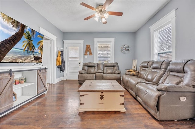 living area featuring dark wood finished floors, a textured ceiling, a barn door, and ceiling fan