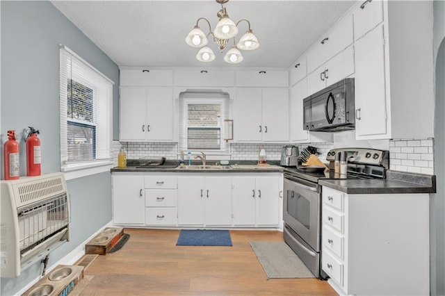 kitchen with stainless steel range with electric stovetop, a sink, heating unit, dark countertops, and black microwave