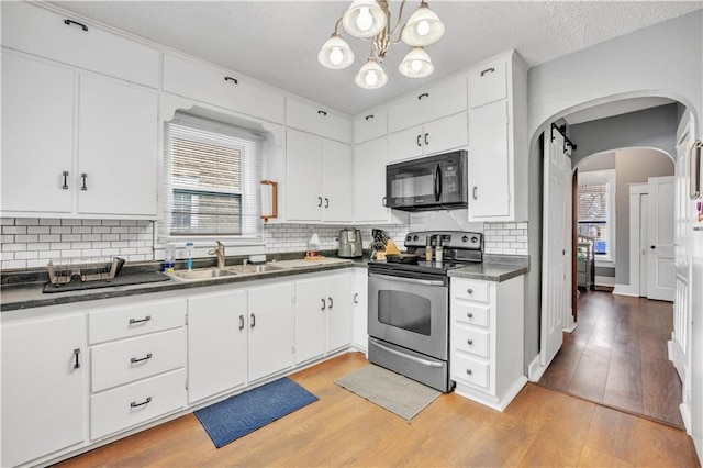 kitchen with dark countertops, stainless steel electric stove, black microwave, and a sink