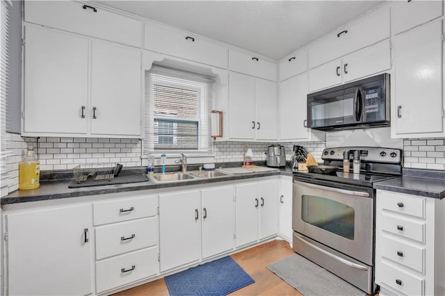 kitchen featuring a sink, stainless steel range with electric cooktop, black microwave, white cabinetry, and dark countertops