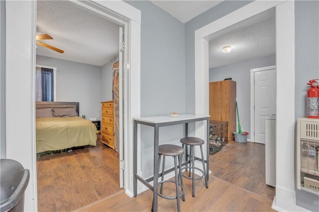 bedroom featuring heating unit, wood finished floors, and a textured ceiling