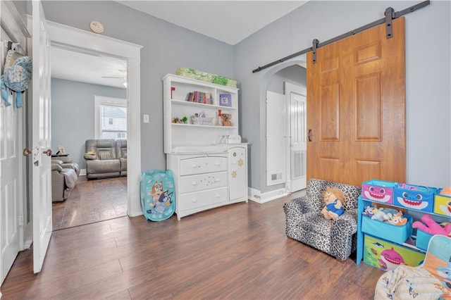 playroom featuring arched walkways, visible vents, a barn door, and wood finished floors