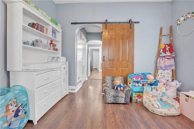 recreation room with wood finished floors, arched walkways, and baseboards