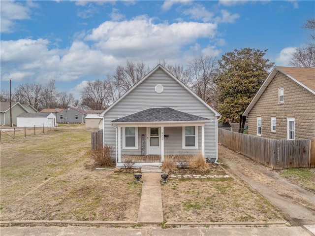 bungalow with a porch, a shingled roof, a front lawn, and fence