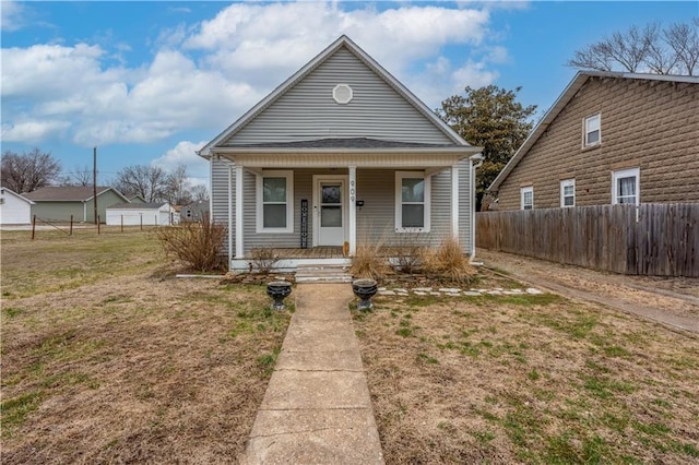 bungalow with a front lawn, fence, and covered porch