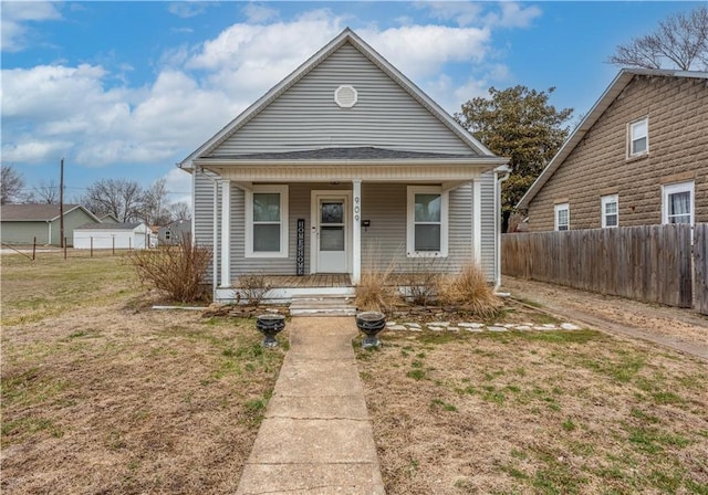 bungalow-style home with a porch, a front yard, and fence