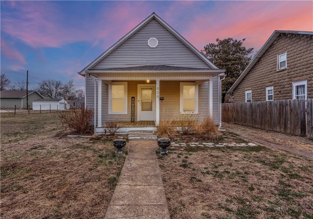 bungalow-style house with a porch, a front lawn, and fence