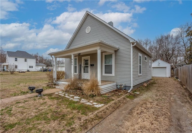 view of front of home featuring a porch, dirt driveway, fence, an outdoor structure, and a garage