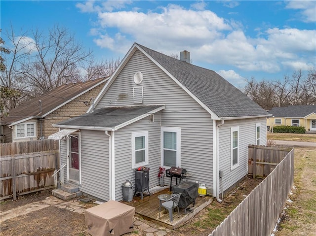 back of property featuring entry steps, roof with shingles, and fence