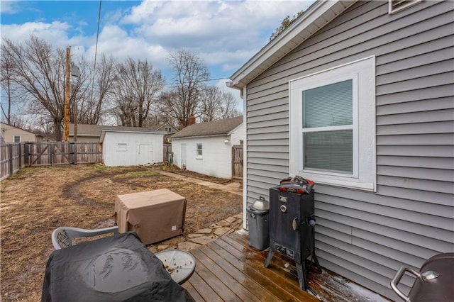 wooden deck with a fenced backyard, a storage unit, and an outdoor structure