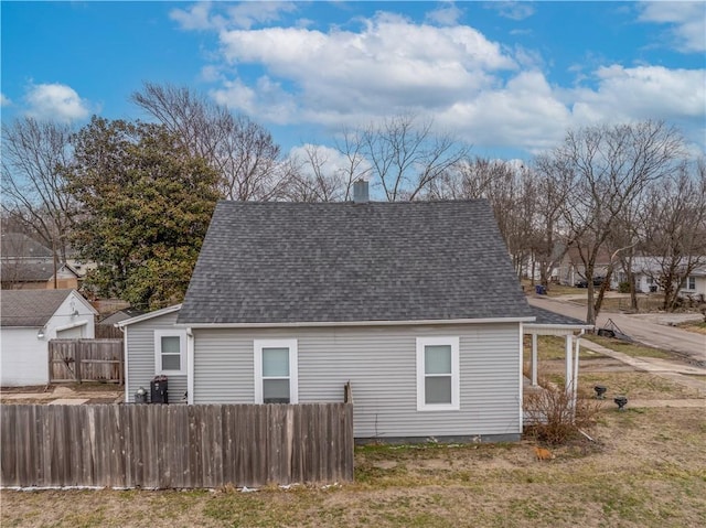 exterior space featuring fence, a chimney, and a shingled roof