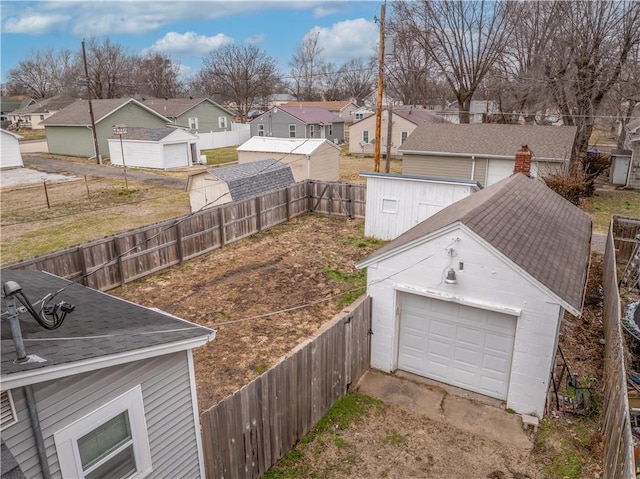 view of yard featuring a garage, a residential view, an outdoor structure, and a fenced backyard