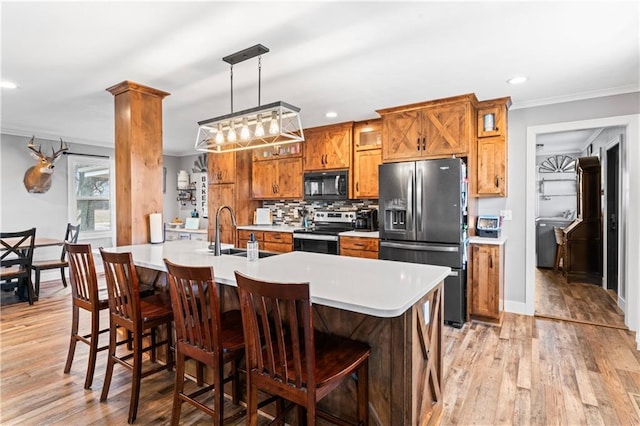 kitchen with ornamental molding, appliances with stainless steel finishes, brown cabinetry, light countertops, and decorative backsplash