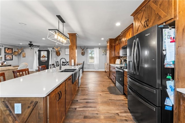 kitchen with wood finished floors, stainless steel range with electric cooktop, black microwave, refrigerator with ice dispenser, and brown cabinets