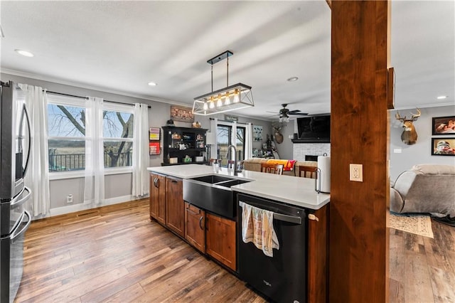 kitchen featuring a fireplace, a sink, open floor plan, dishwasher, and stainless steel fridge