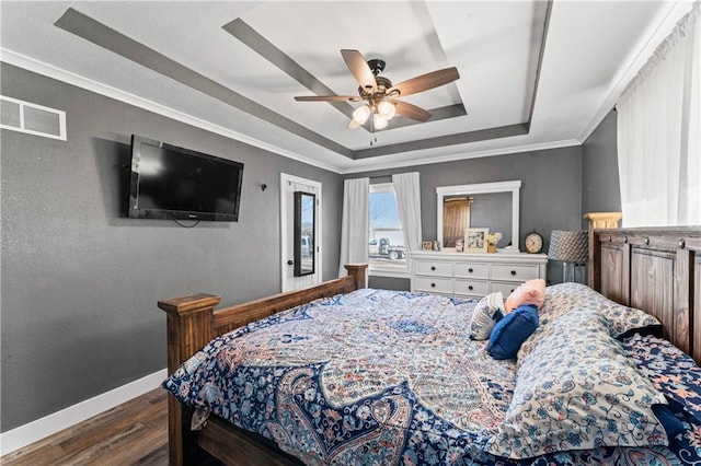 bedroom featuring dark wood-style floors, visible vents, baseboards, ornamental molding, and a raised ceiling