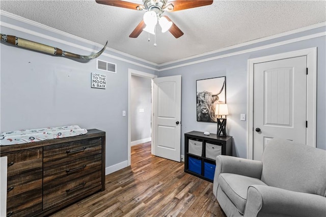 sitting room featuring wood finished floors, baseboards, visible vents, a textured ceiling, and crown molding