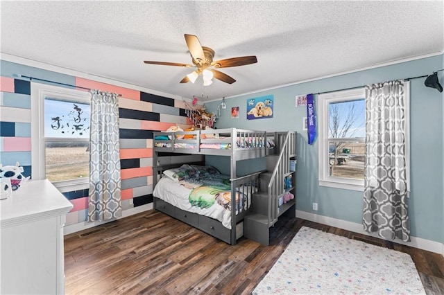 bedroom featuring ceiling fan, baseboards, a textured ceiling, and wood finished floors