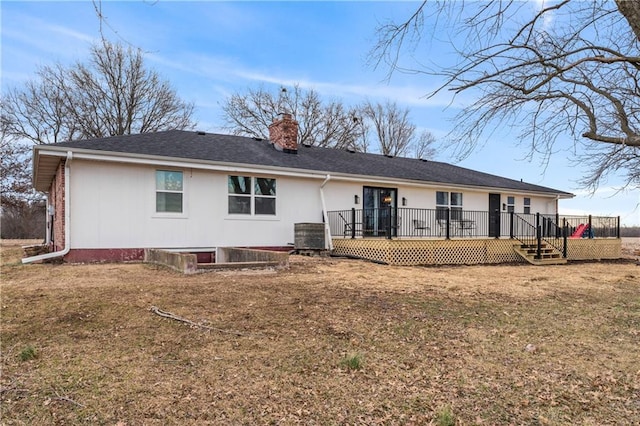 rear view of property with a lawn, a deck, and a chimney