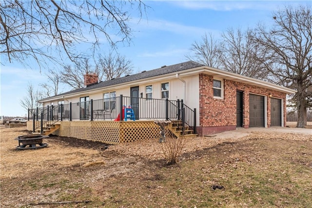 view of front of property with driveway, an outdoor fire pit, a chimney, a deck, and brick siding