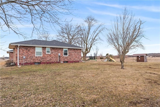 exterior space featuring an outbuilding, a playground, a lawn, and brick siding