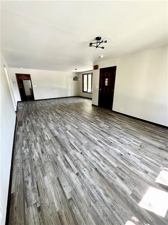 unfurnished living room with visible vents and wood finished floors